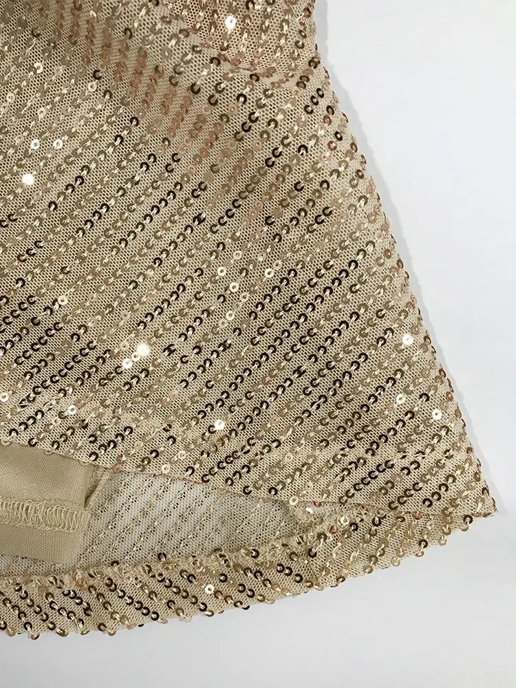 Une robe de vacances à bretelles croisées en sequins dorés scintillants, présentant un tissu délicatement texturé avec un motif diagonal subtil.