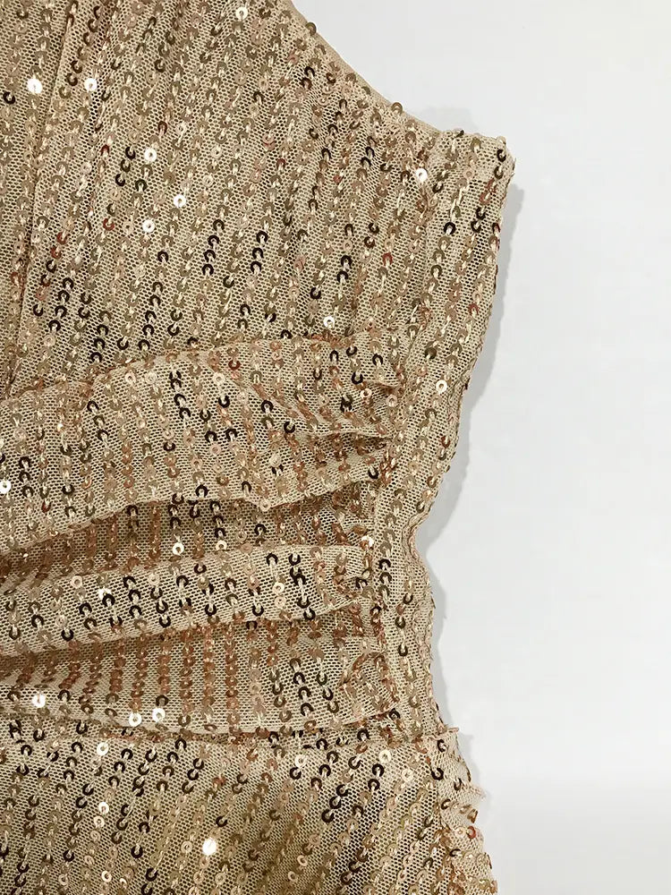 Une robe de vacances à bretelles croisées en sequins dorés scintillants avec des détails froncés.