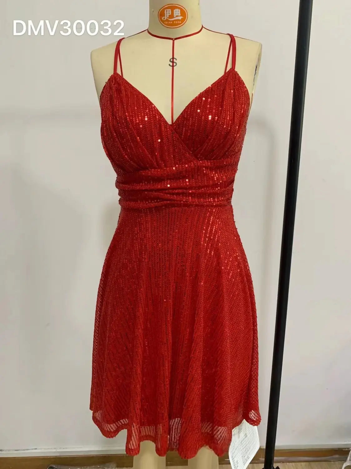 Une robe de vacances rouge à bretelles croisées en sequins scintillants, avec de fines bretelles spaghetti et un corsage ajusté, présentée sur un mannequin.