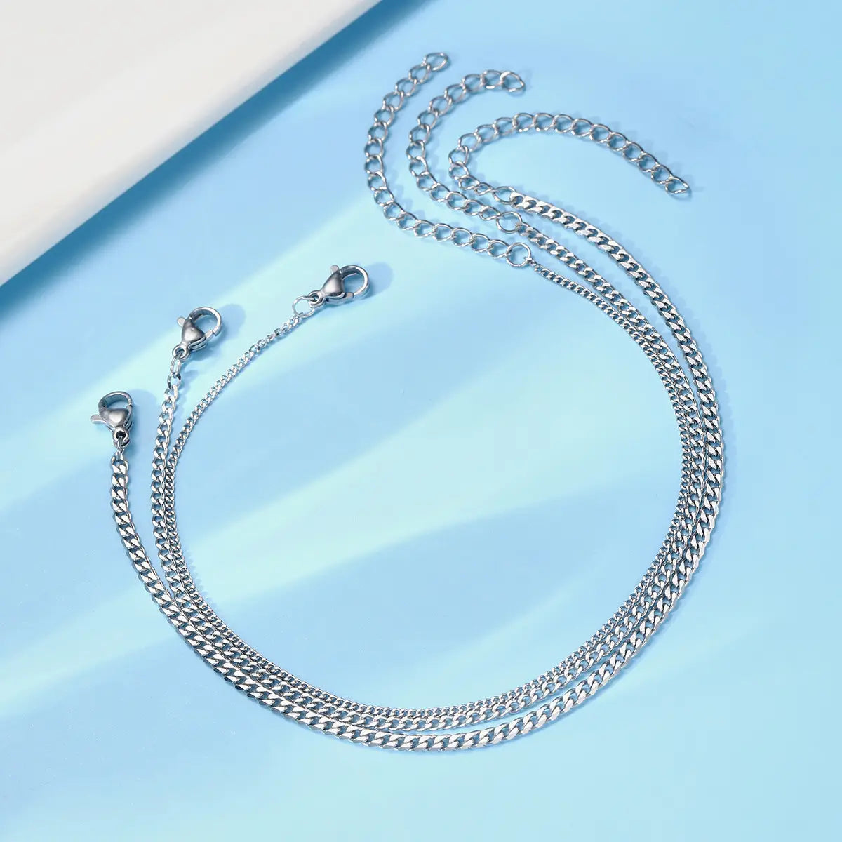 Unisex silver layered Cuban and Figaro link bracelet set featuring a silver-toned curb chain necklace with sleek interlocking links and secure lobster clasps.