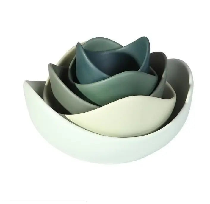 A set of five nested ceramic bowls in a pastel pink lotus flower design with smooth matte finishes in white gray and muted green.