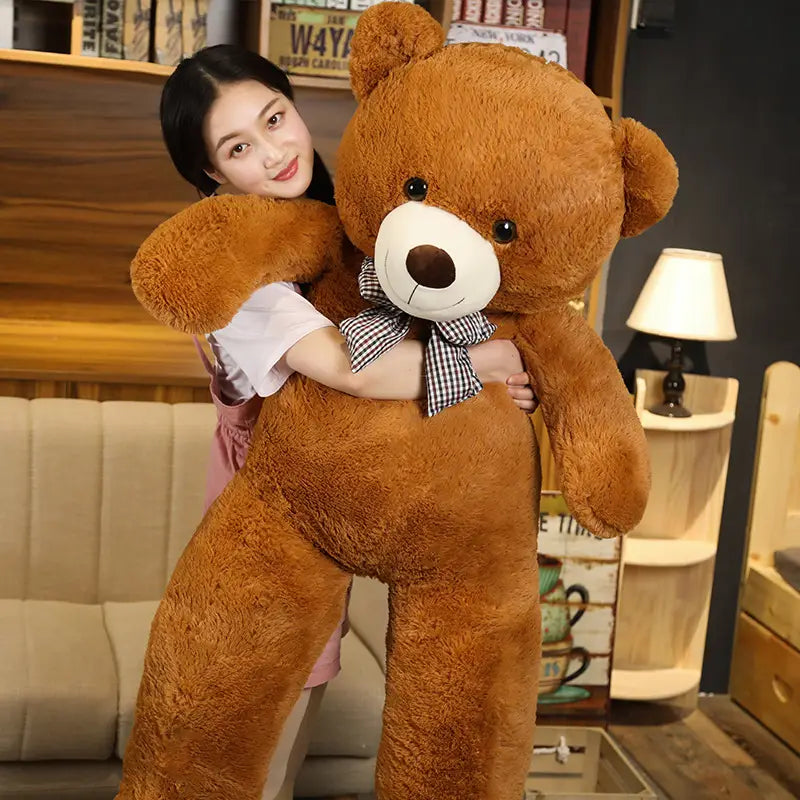 Ein flauschiger Teddybär in mittlerem Braun mit weißem Schnäuzchen und schwarzen Knopfaugen, der als Teddybär-Plüschtier mit karierter Fliege und karierter Fliege dargestellt ist.