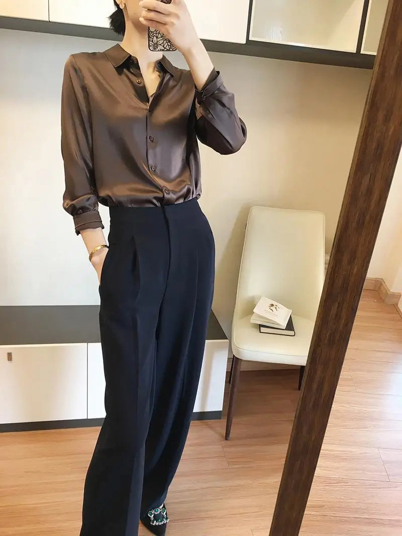 A sleek satin-finish brown long sleeve satin button down silk blouse with rolled sleeves.