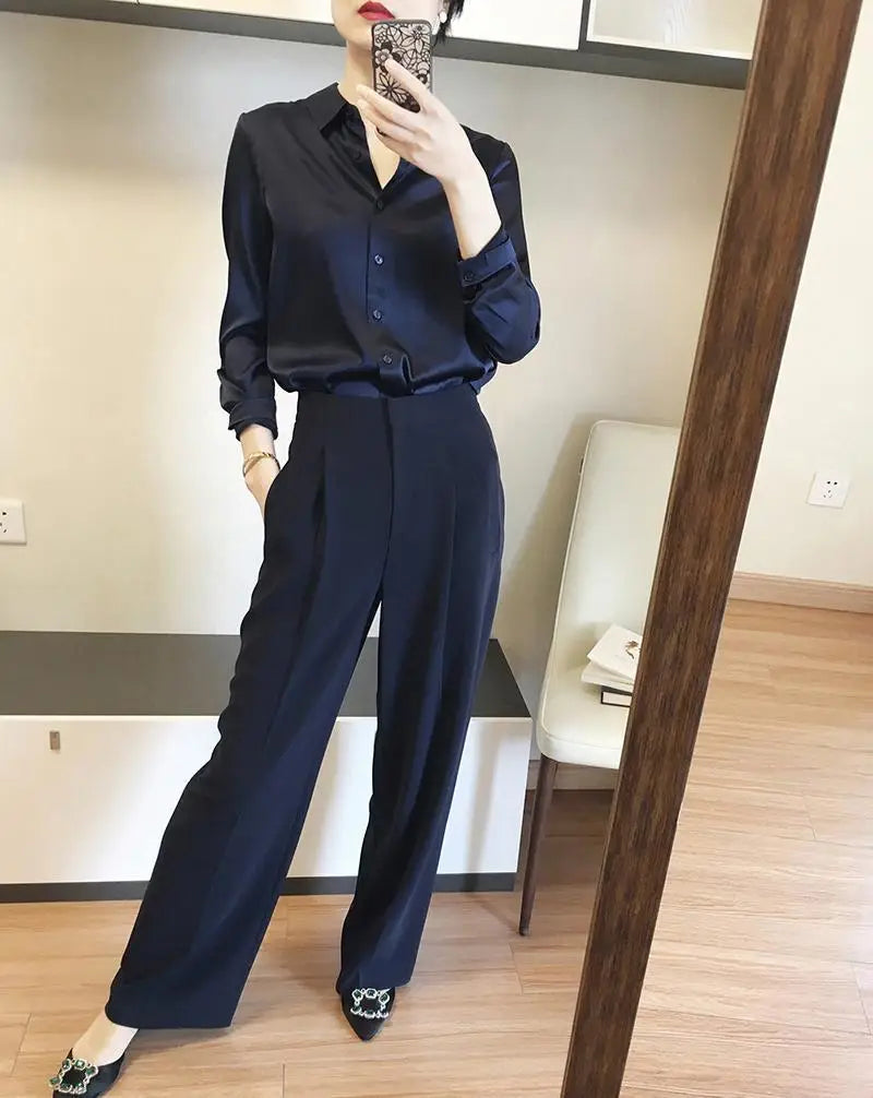 Elegant long sleeve satin button down silk blouse in navy blue featuring a classic collar and smooth texture.