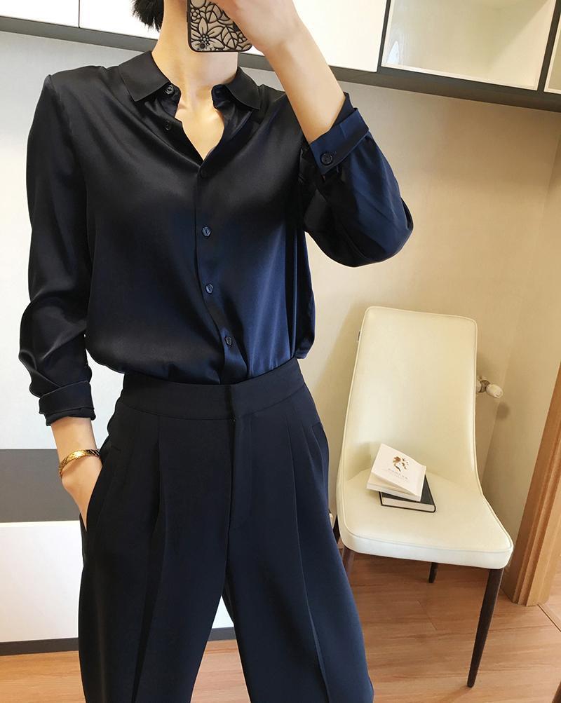 A sleek navy blue satin button-down blouse with long sleeves and a classic collar made of elegant silk for formal wear.