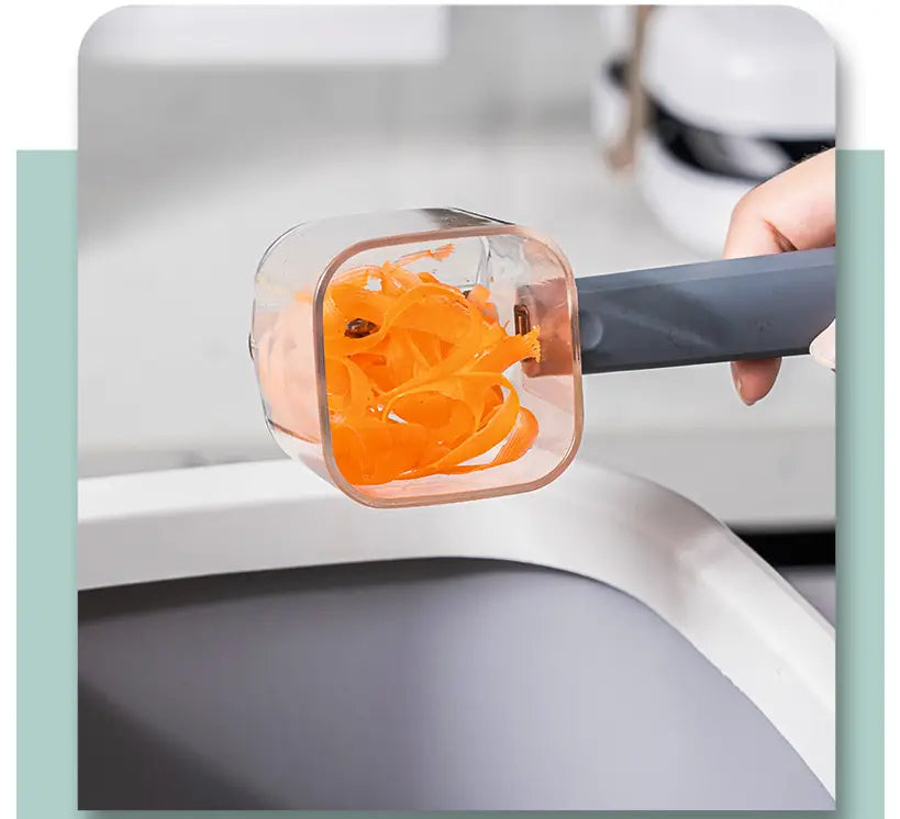 Éplucheur de légumes en acier inoxydable avec poignée grise, doté d’une lame carrée en plastique transparent retenant des copeaux de carotte orange.