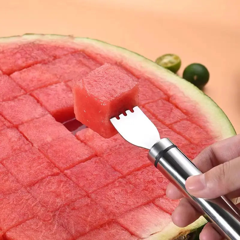 Une fourchette de découpage de pastèque en acier inoxydable élégante et épurée, avec une tête à quatre dents qui soulève une tranche parfaitement cubée d’un fruit rouge juteux.
