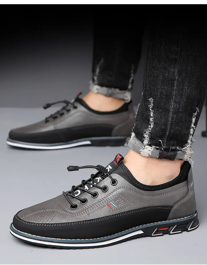 Chaussures de sport imperméables pour homme en cuir véritable gris et noir, avec design décontracté à lacets, dessus texturé, semelle en caoutchouc contrastée et détails de branding rouges discrets.
