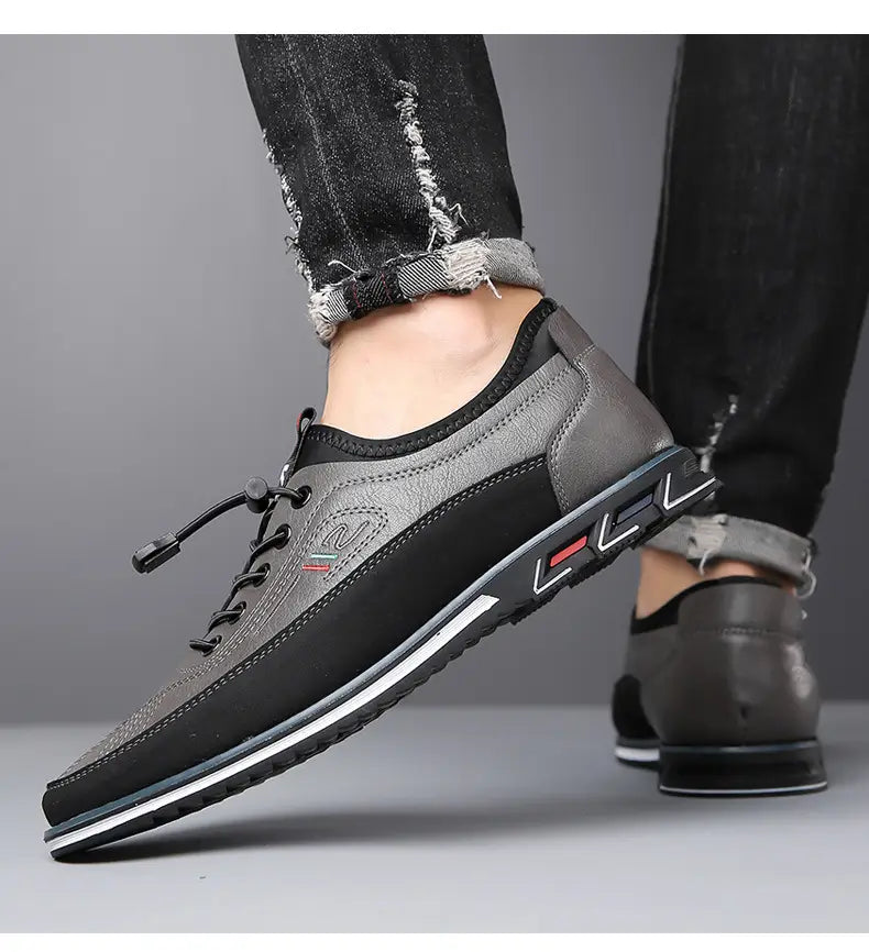 Chaussures de sport imperméables pour homme en cuir véritable gris et noir, avec design à lacets, dessus texturé, panneaux latéraux contrastés et une bande blanche le long de la semelle.