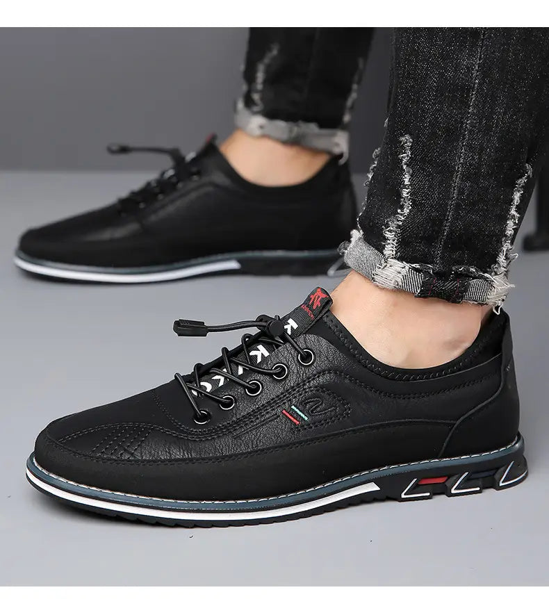 Chaussures de sport imperméables pour homme en cuir véritable noir, lacets en cuir, avec semelle en caoutchouc blanche et grise et détails de branding rouges et verts discrets sur le côté.