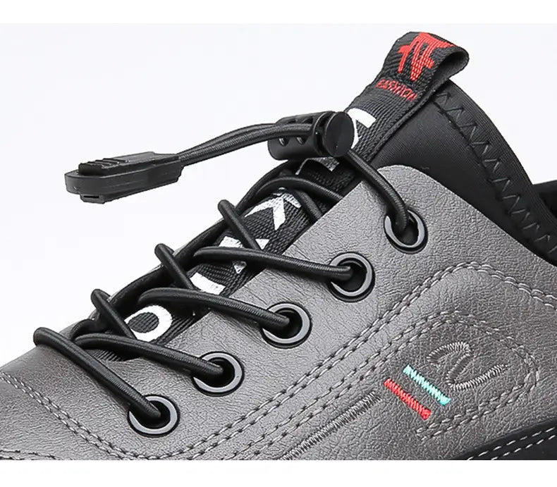 Chaussures de sport imperméables pour homme en cuir véritable grises, avec lacets noirs et un logo rouge sur la languette.