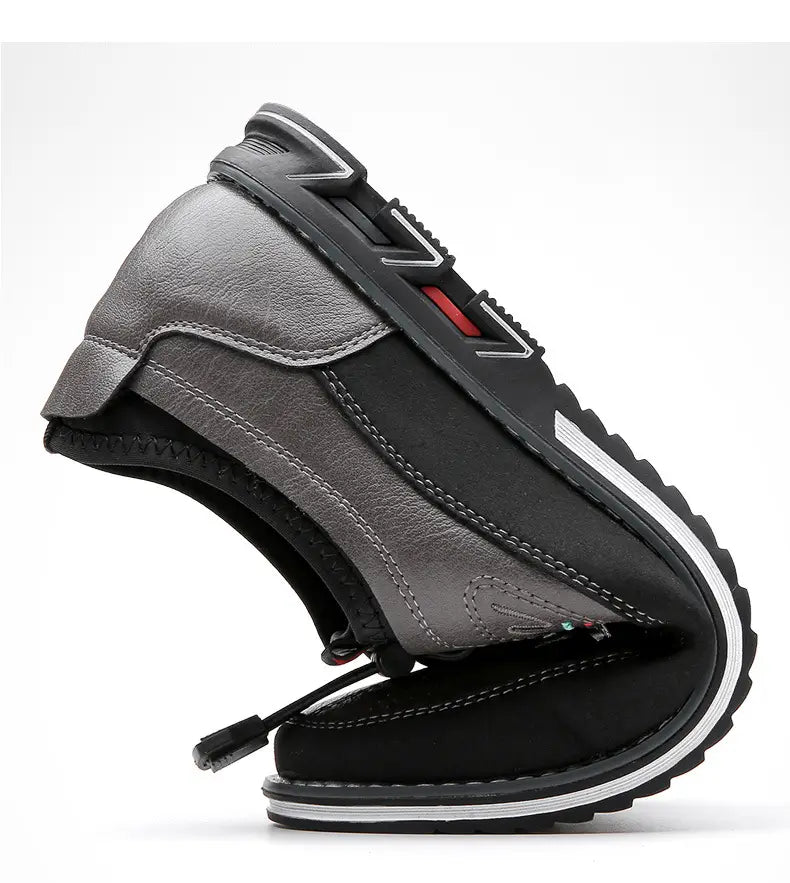 Chaussure de sport imperméable pour homme en cuir véritable gris et noir, avec design à enfiler, semelle en caoutchouc texturée, accents de coutures blanches et détails rouges au talon.