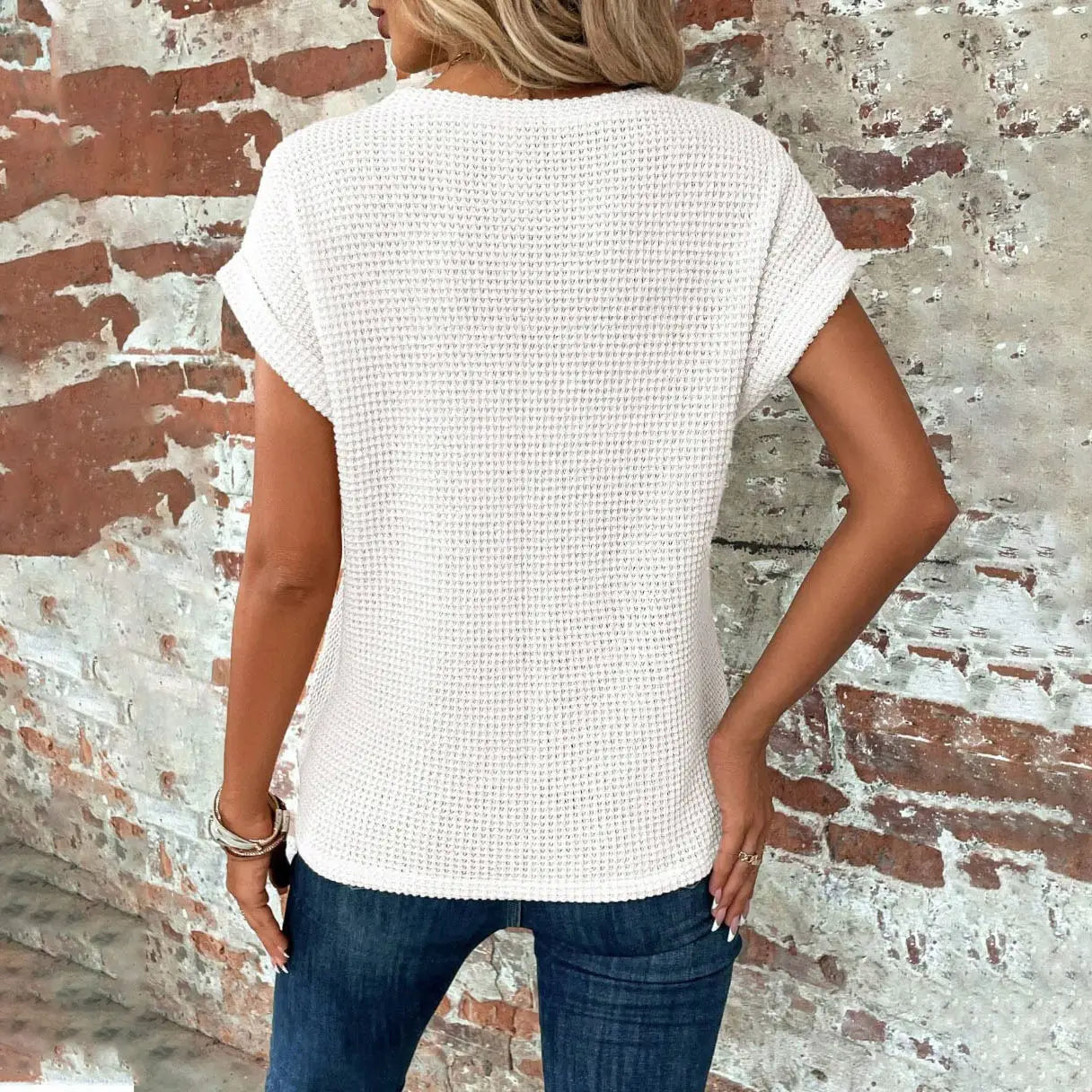 A white waffle-knit relaxed fit short sleeve top for women made of breathable knit fabric.