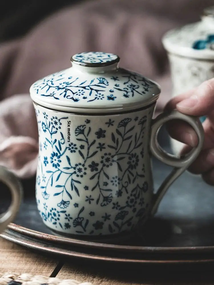 A white ceramic tea mug with infuser and lid featuring delicate blue floral patterns and a sturdy handle with a 300ml capacity.