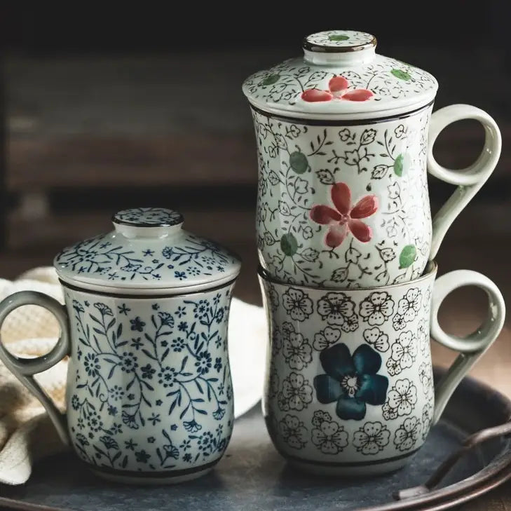White ceramic tea mug with infuser and lid featuring delicate blue and red floral patterns and a 300ml capacity.