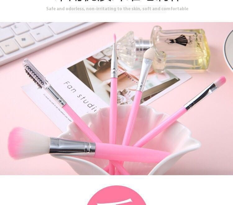 Ensemble de cinq pinceaux de maquillage roses avec viroles en argent et des poils doux dégradés disposés dans un bol en céramique blanc pour une application cosmétique professionnelle.