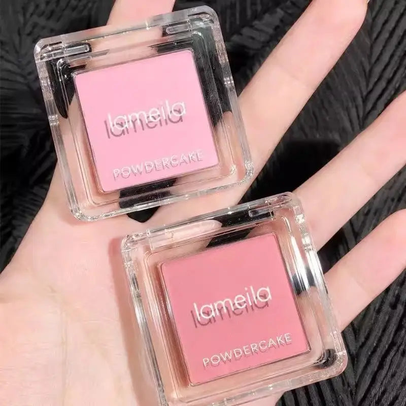 Two transparent square monochrome powder blush compacts with pink powder and lameila powdercake branding designed for facial application.