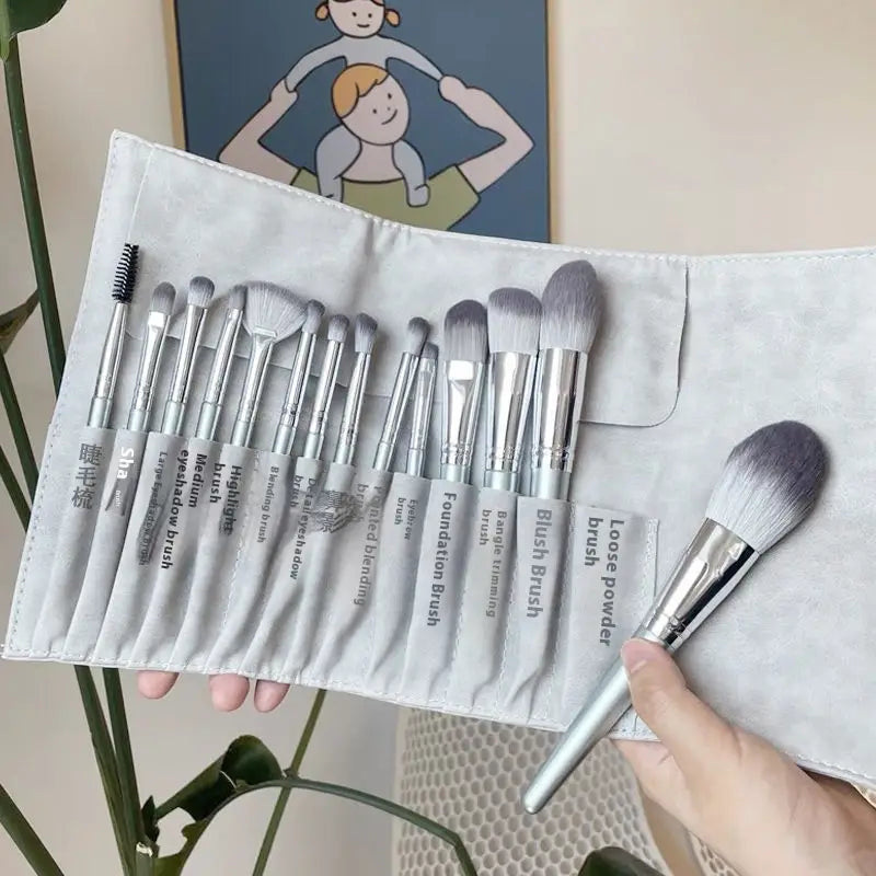 a sleek silver and gray makeup brush set with 15 pieces in a soft light-gray fabric case with labeled slots for each brush
