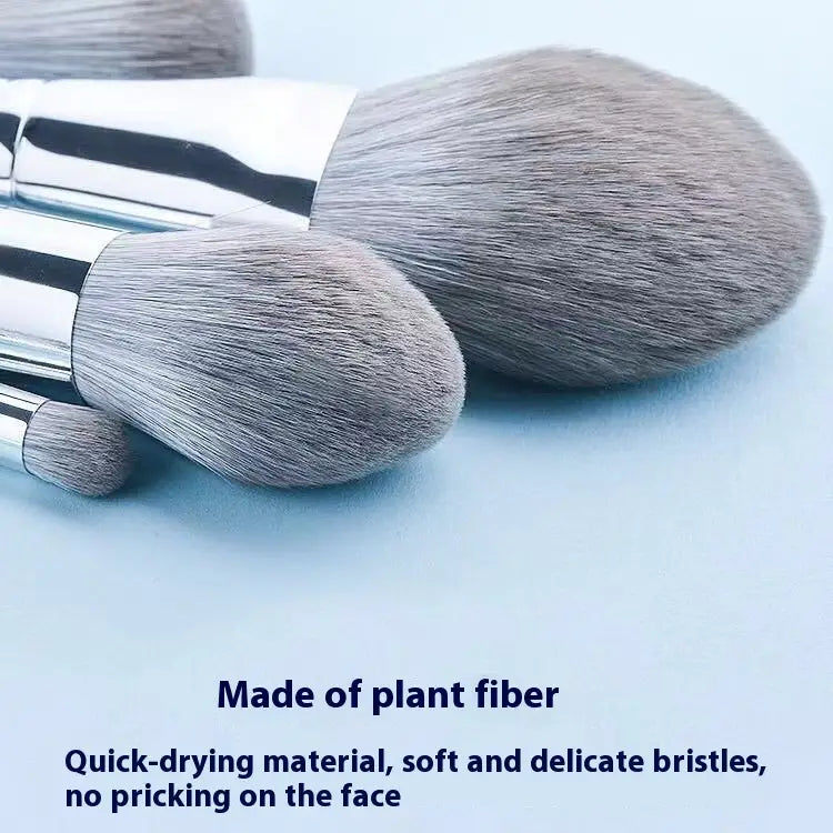 Set of three soft gray plant fiber makeup brushes with sleek silver handles included in a makeup brush set with 15 silver pieces and case.