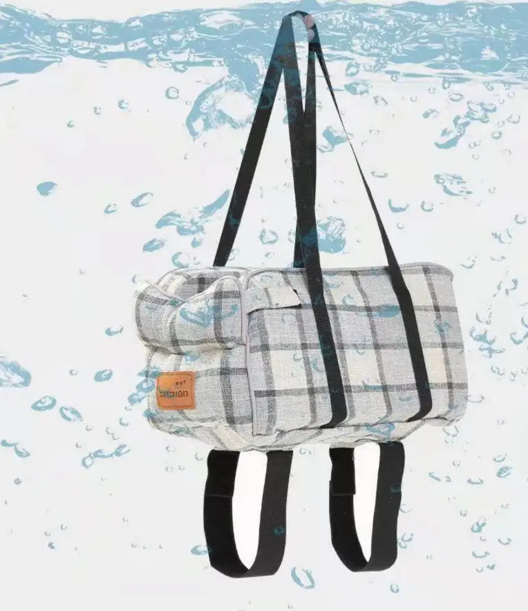 A plaid-patterned soft-textured duffel pet carrier bag with black straps and a small orange brand tag designed for breathable travel use.