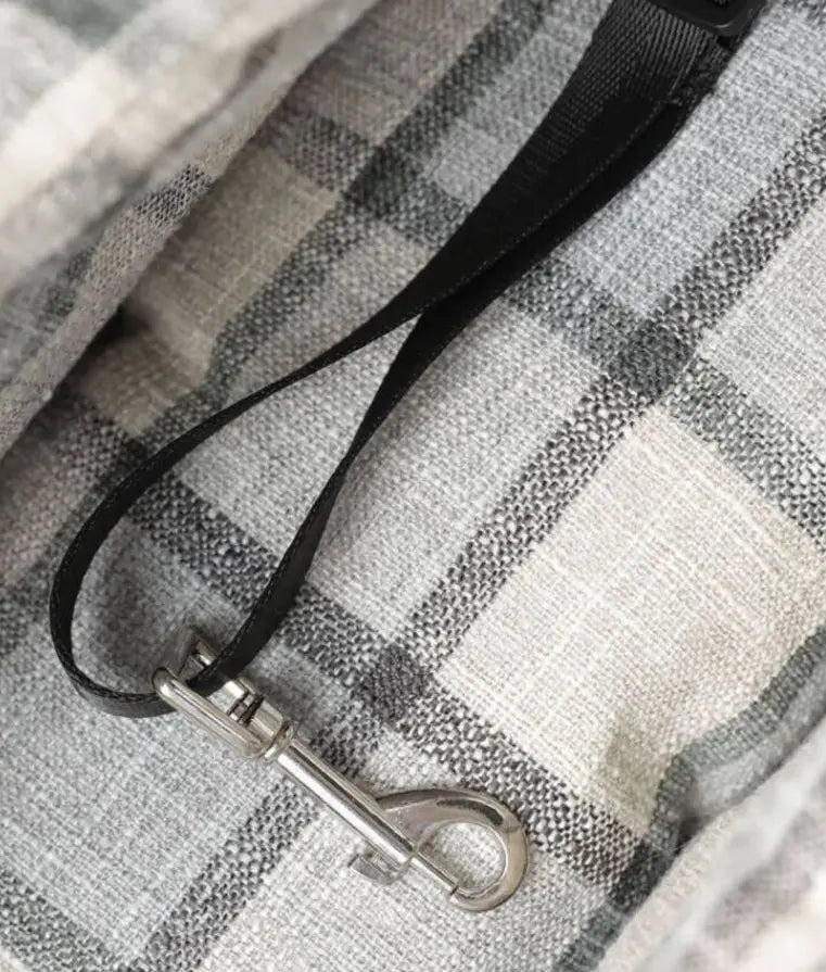 Black fabric leash with a silver-toned metal clasp attached to a plaid pet carrier bag breathable travel dog purse.