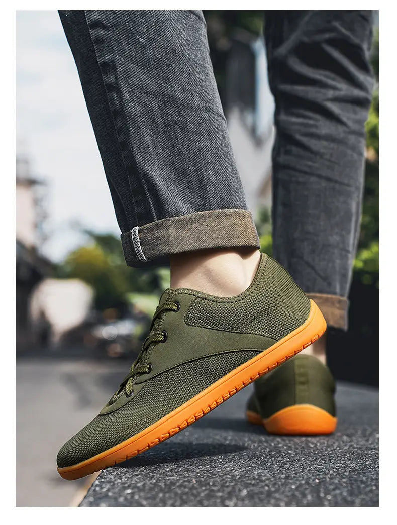 Men’s wide toe breathable mesh running sneakers in olive green canvas with a vibrant orange rubber sole.