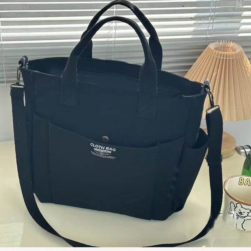 Black canvas commuter tote bag with large capacity, leather straps, sturdy handles, and a detachable shoulder strap.
