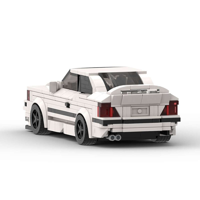 Modèle de BMW E30 M3 construit en Lego blanc, avec bandes de course noires et feux arrière rouges, présenté depuis le côté arrière, dans le modèle de voiture de sport en briques E36, jouet de 509 pièces.