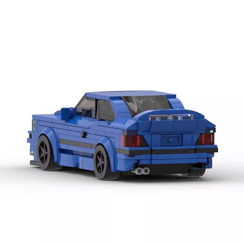 Jouet de modèle de voiture de sport E36 construit en Lego bleu, avec roues noires et feux arrière rouges, présenté depuis le côté arrière, réalisé à partir de 509 briques.