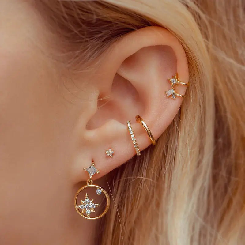 Ensemble boucles d’oreilles et manchettes « étoile et lune » en forme de papillon, comprenant des manchettes d’oreille à thème étoile en finition dorée, rehaussées d’accents en cristaux transparents, ainsi qu’un pendentif circulaire suspendu avec un motif d’étoile intégré.