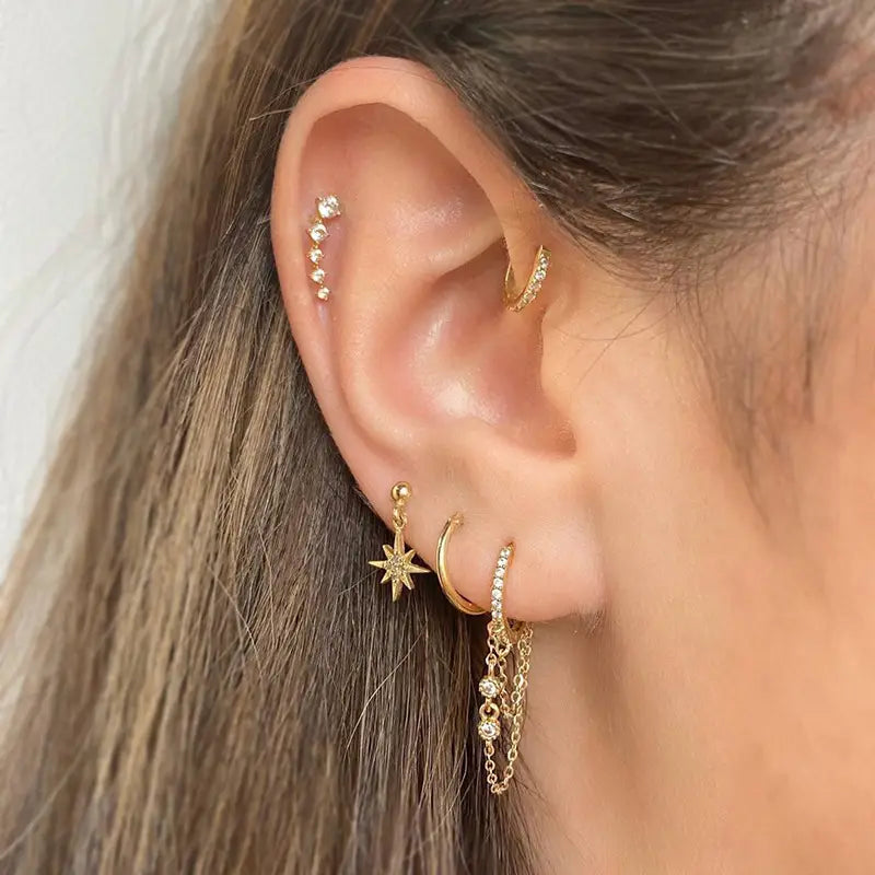 Ensemble boucles d’oreilles et manchettes « étoile et lune » en forme de papillon, comprenant des clous, des anneaux et un charm en forme d’étoile suspendu à finition dorée, ornés de cristaux transparents.