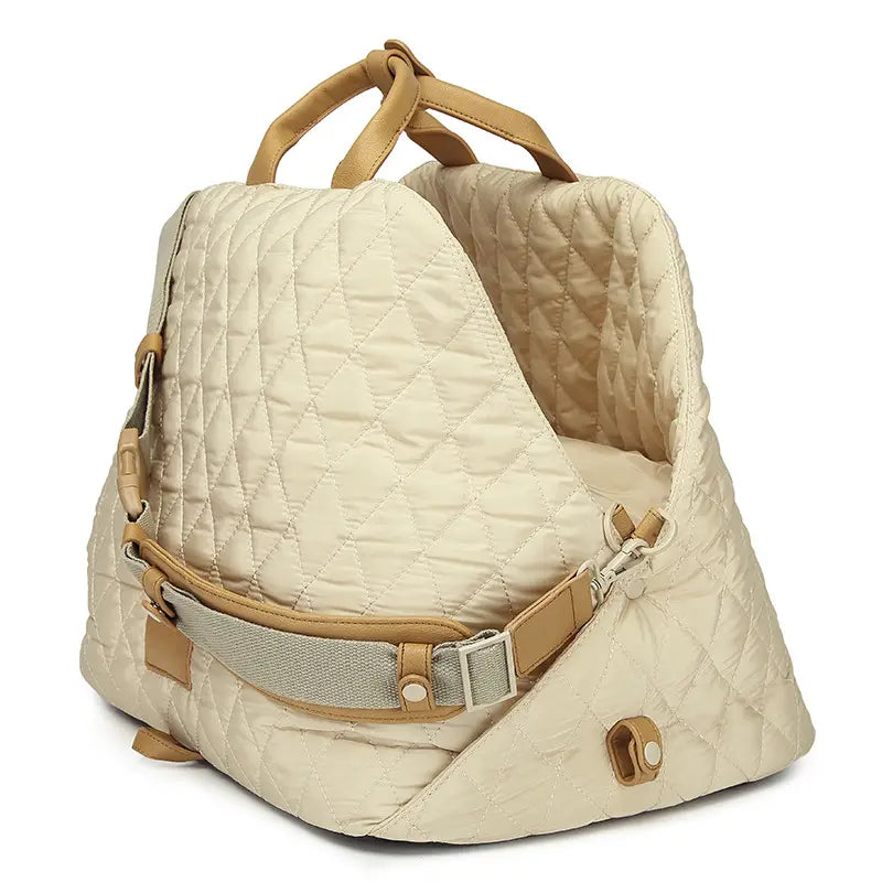 Cream-colored quilted travel pet carrier bag with tan leather handles and straps for easy carrying.
