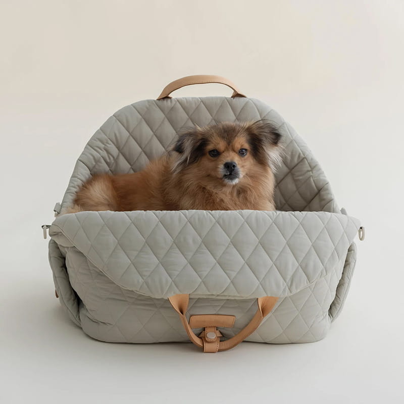 A cozy light gray quilted travel pet carrier bag with tan leather handles and a front flap closure.