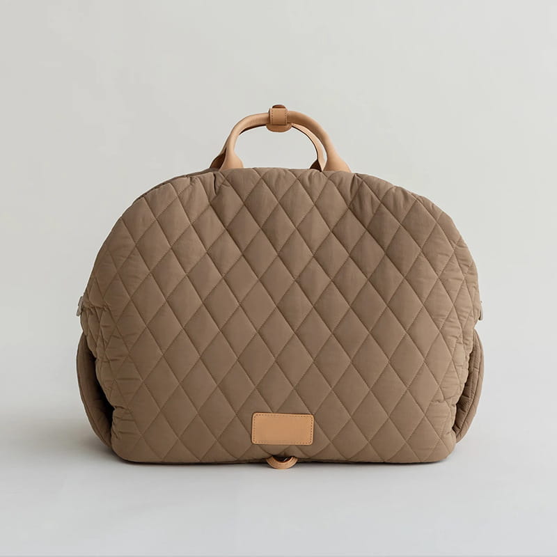 Beige quilted travel pet carrier bag with tan leather handles and a matching leather patch.