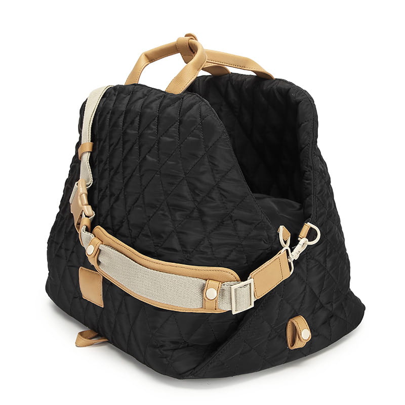 Black quilted travel pet carrier bag with tan leather handles and straps designed for comfortable and stylish pet transportation.