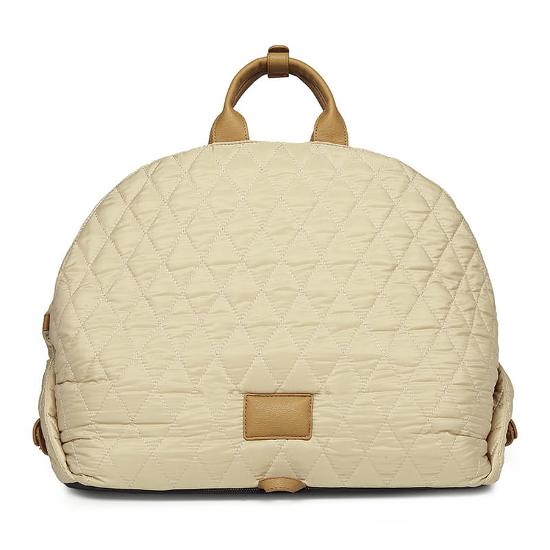 beige quilted travel pet carrier bag with tan leather handles and a matching rectangular brand patch.