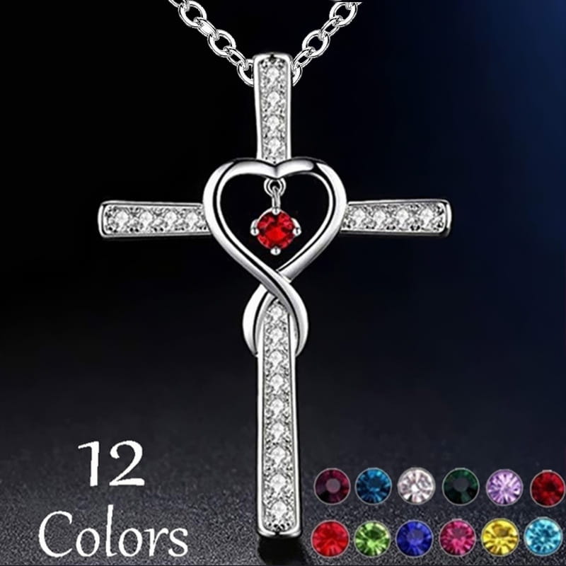 Silver cross pendant necklace featuring a heart-shaped center with a red birthstone and clear crystals along the arms in the infinity love heart cross birthstone crystal necklace design.
