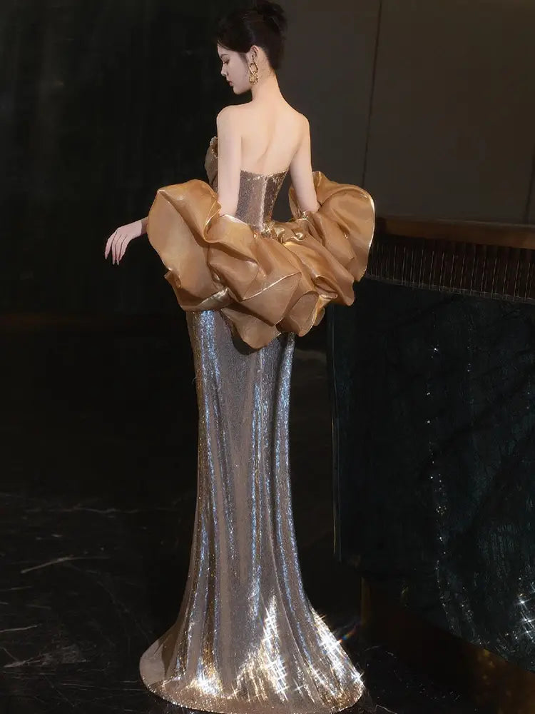 A gold sequin evening gown featuring a shimmering silver sequined skirt and a dramatic gold satin ruched bodice with voluminous puff sleeves.