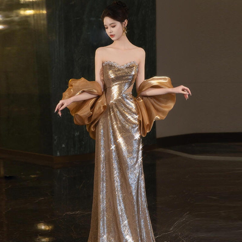 A gold sequin evening gown featuring shimmering sequins, voluminous satin puff sleeves, and a fitted bodice.