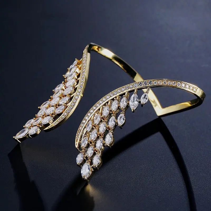 Gold-toned angel wing cuff bracelet featuring marquise-cut clear crystals and smaller pave-set stones along the edges in a marquise crystal angel wing bangle bracelet design.