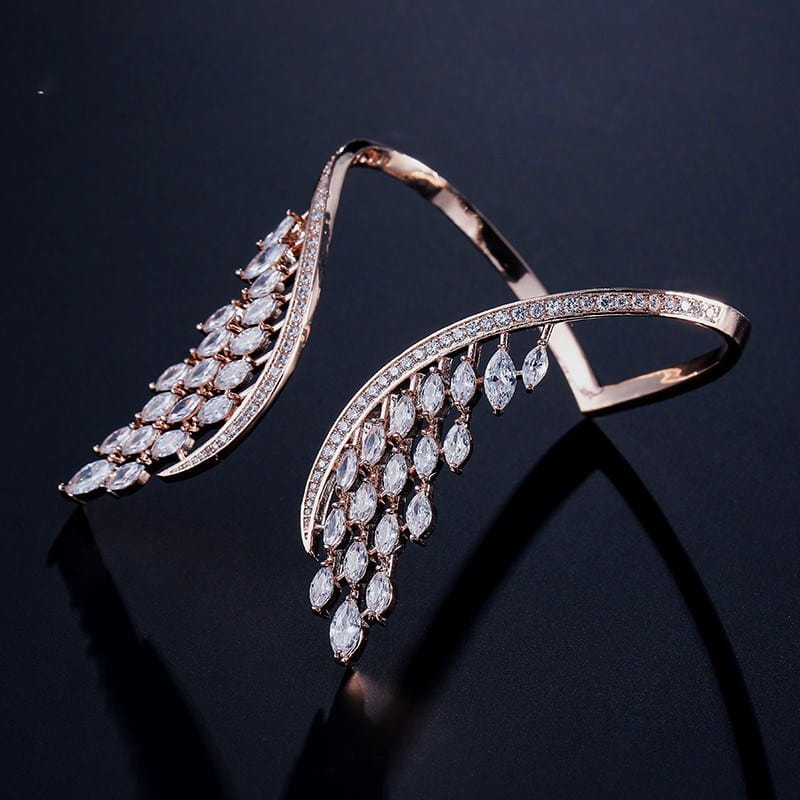 A rose gold marquise crystal angel wing bangle bracelet featuring wing-shaped design adorned with marquise-cut clear crystals and smaller pavé stones along its curves.