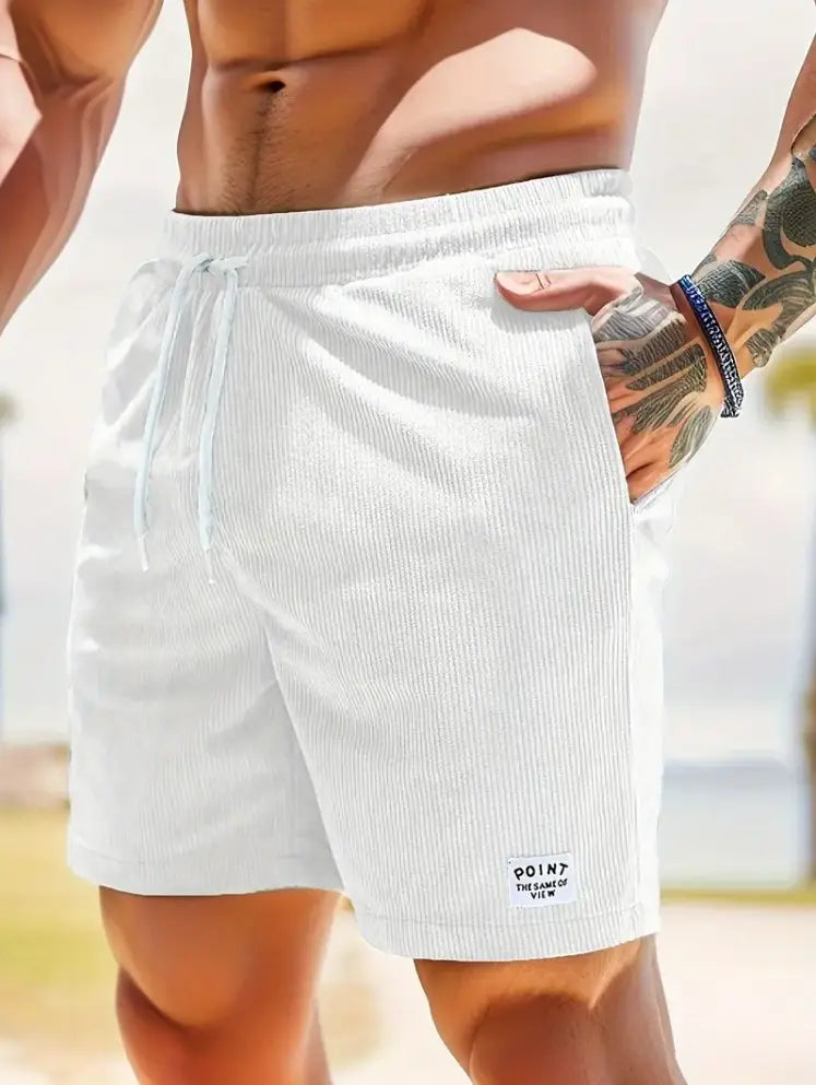 Shorts en velours côtelé blanc à cordon de serrage pour hommes, avec une ceinture et une petite étiquette de marque « point » sur la partie inférieure droite de la jambe, conçue pour les vêtements de sport.