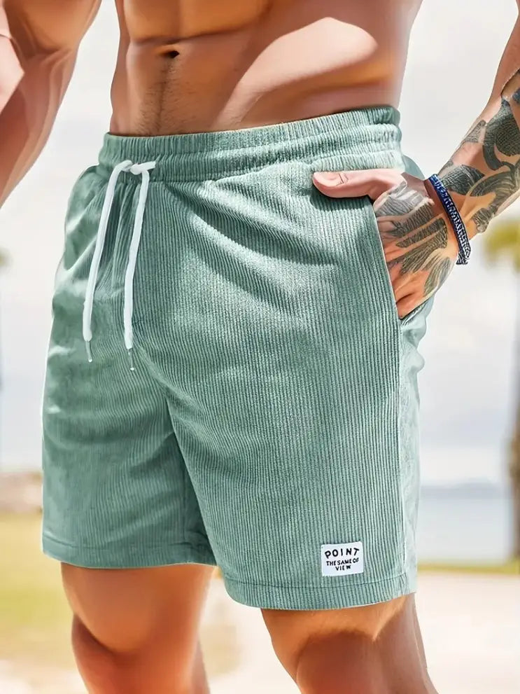 Shorts en velours côtelé vert clair à cordon de serrage pour hommes, avec des cordons de serrage blancs et une petite étiquette « point de vue » identique sur la partie inférieure droite de la jambe, conçus pour un usage sportif.