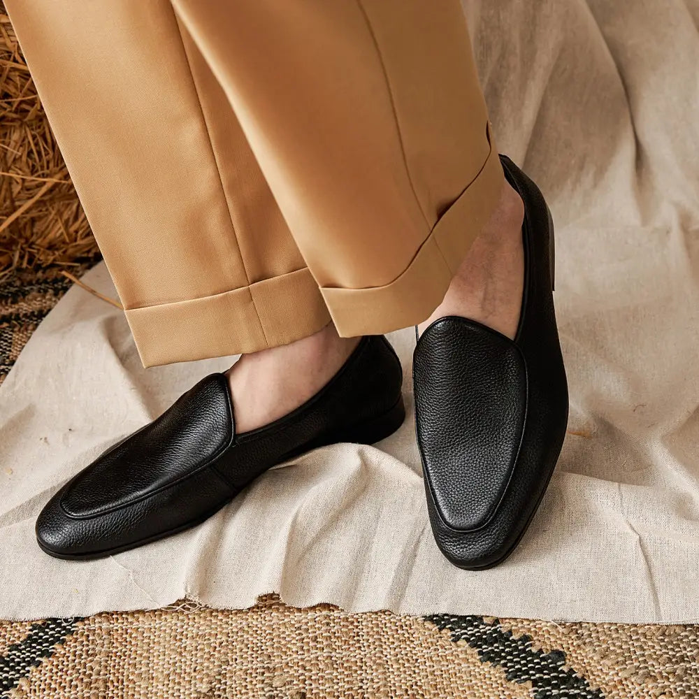 Black leather loafers with a textured cowhide surface and classic slip-on pointed toe design.