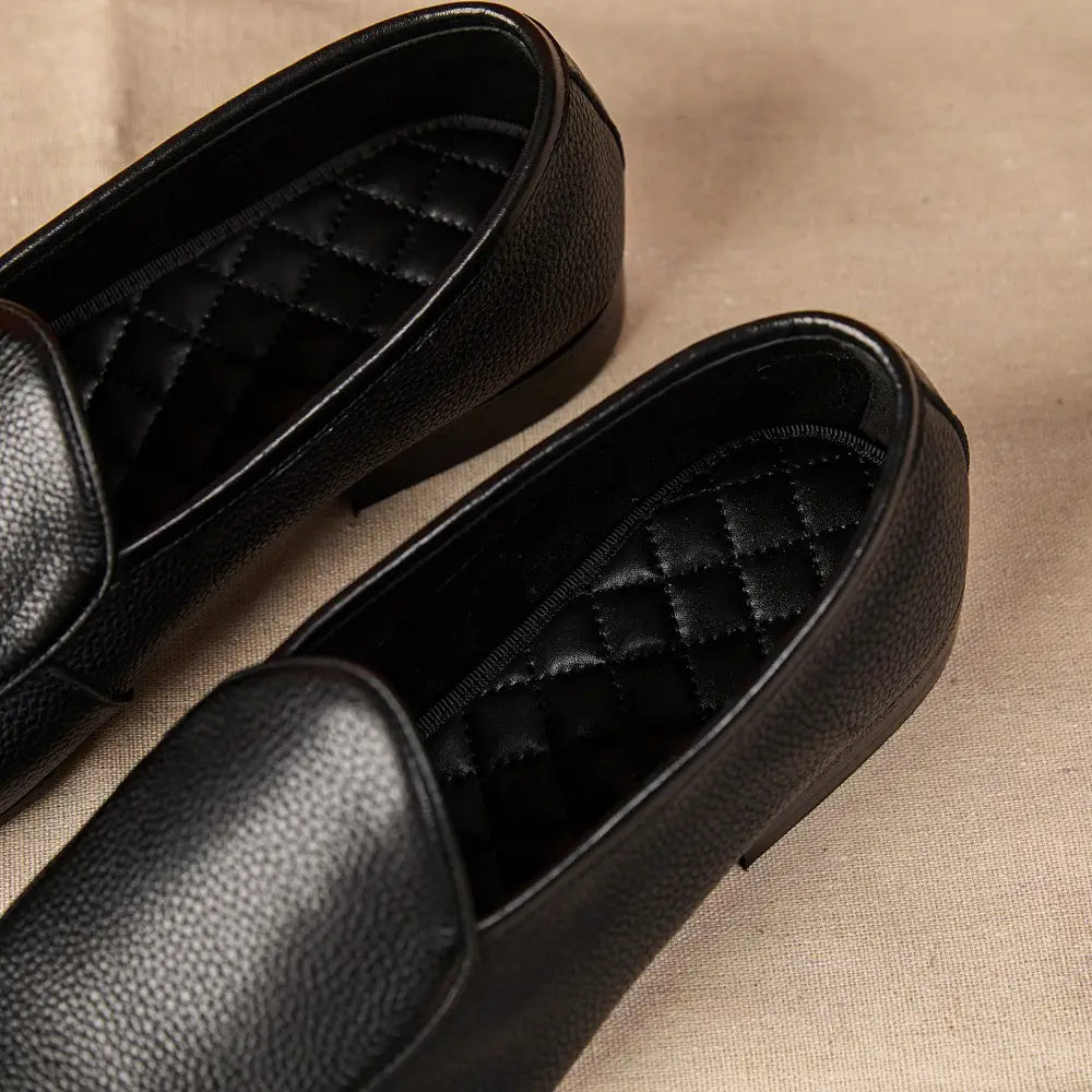 Black textured cowhide leather pointed toe loafers with a quilted interior lining.