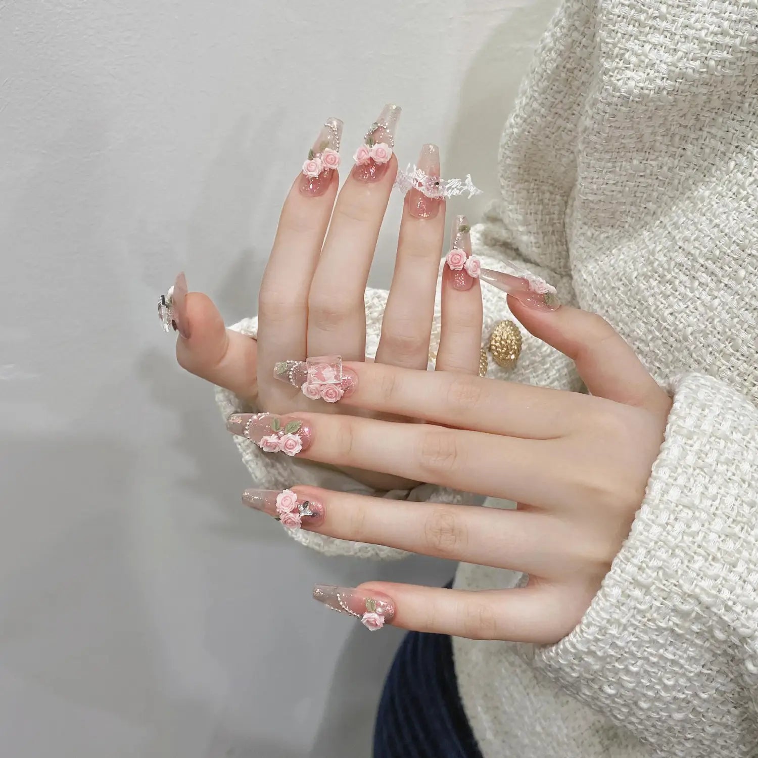 Handmade pink floral almond press on nails with delicate floral embellishments and a translucent glossy acrylic finish with glitter.