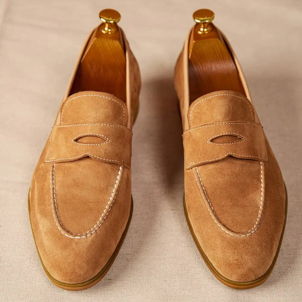 Chaussures de type loafers en suède couleur camel au design classique sans lacets avec surpiqûres contrastantes blanches.