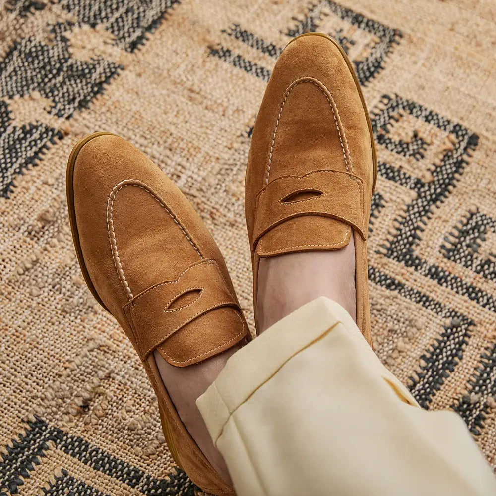 Chaussures de type loafers en suède couleur camel au design classique sans lacets avec surpiqûres contrastantes blanches.