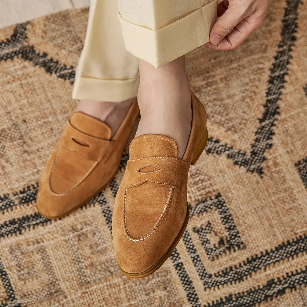 Chaussures de type loafers en suède couleur camel au design classique sans lacets avec surpiqûres contrastantes blanches.