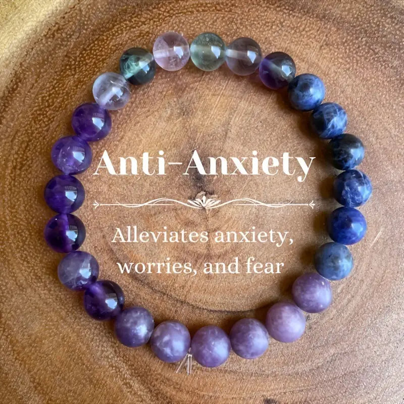 A multicolor gradient fluorite beaded bracelet composed of smooth polished beads in varying shades of purple blue and subtle greenish hues with a crystal accent.
